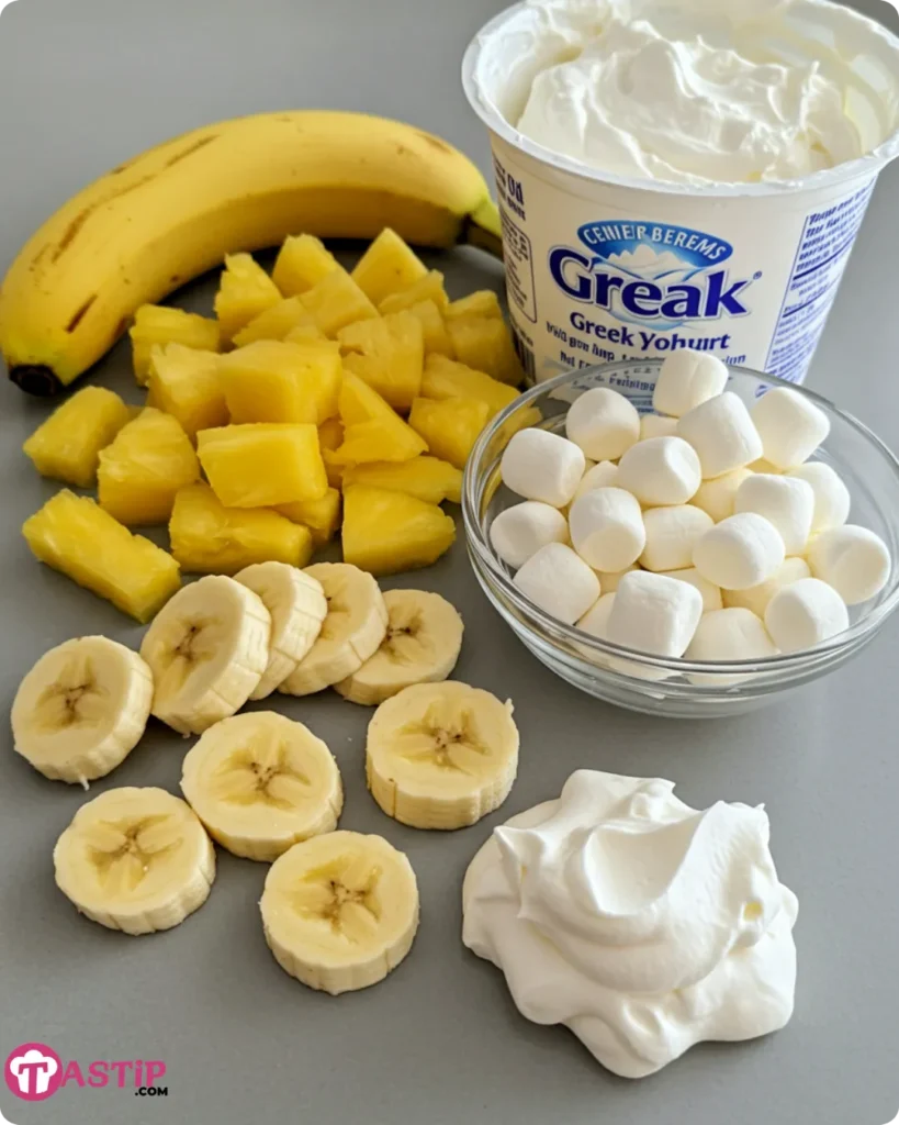 All ingredients for Banana Split Fluff, including bananas, crushed pineapple, marshmallows, whipped topping, and more